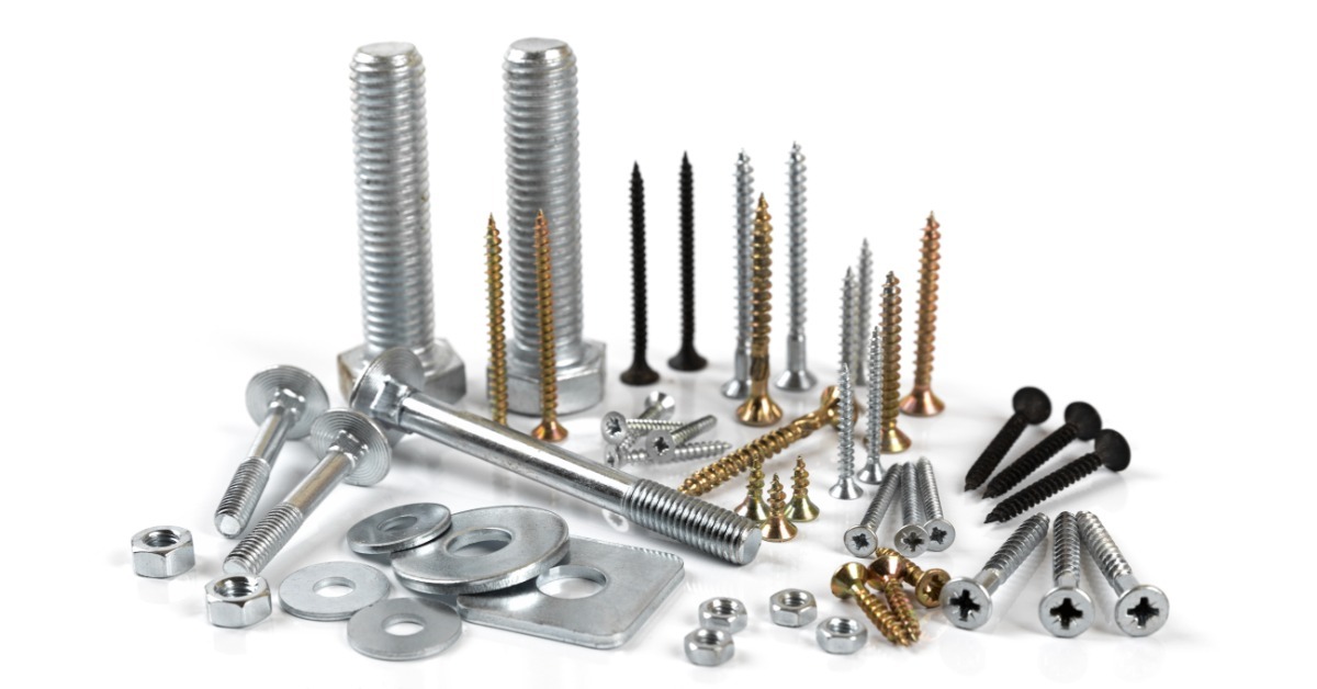 Assorted metal screws, bolts, nuts, and washers arranged on a white surface in different sizes and finishes.
