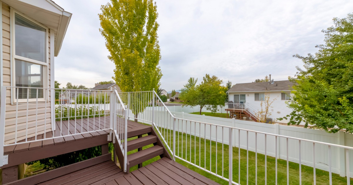 A two tiered deck with metal railings. The deck is high off the ground and can see into the yard of the house next door.