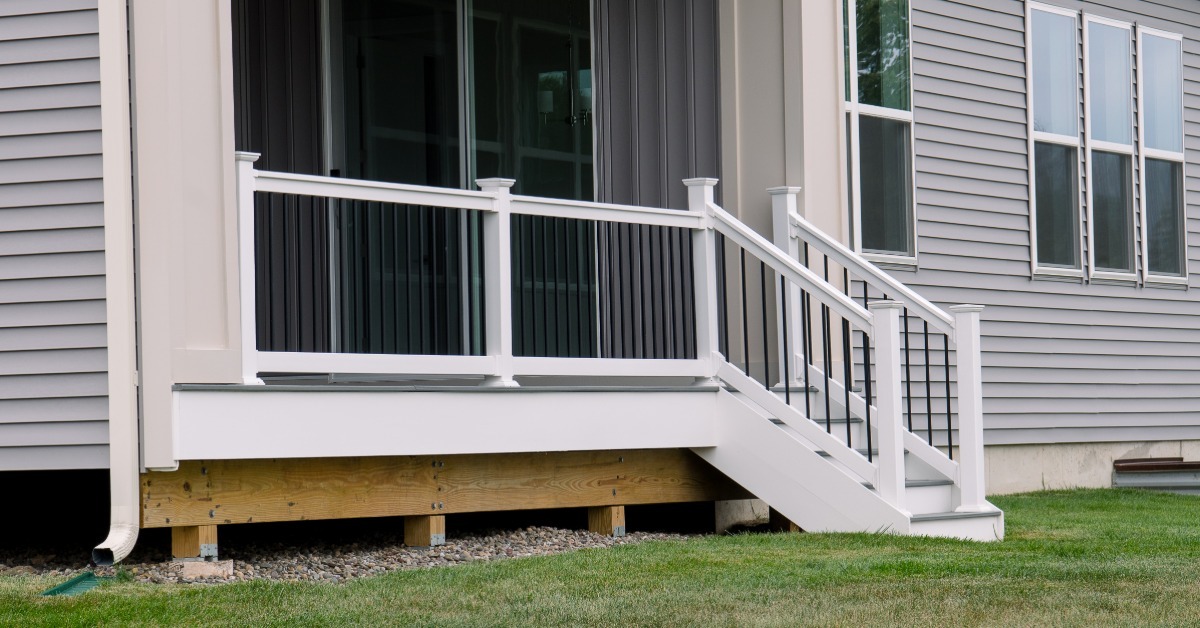 A small deck that's built into the house. It has a short railing and some steps that lead out to the yard.