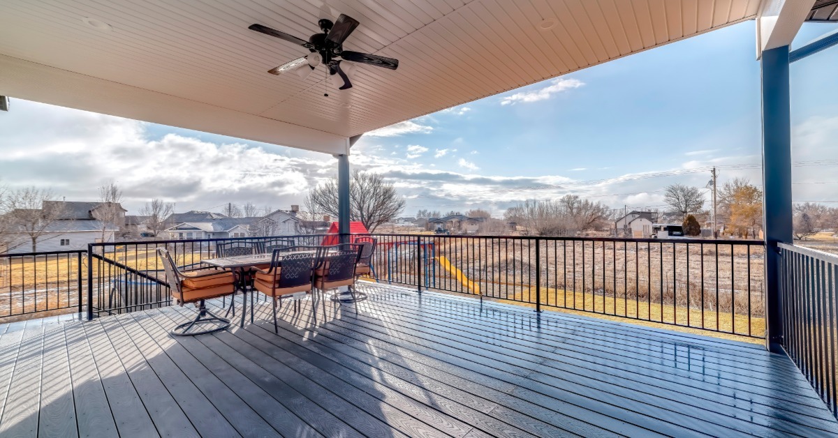 A large open deck with a table and chairs at the far end of it. There is a black railing surrounding the whole thing.