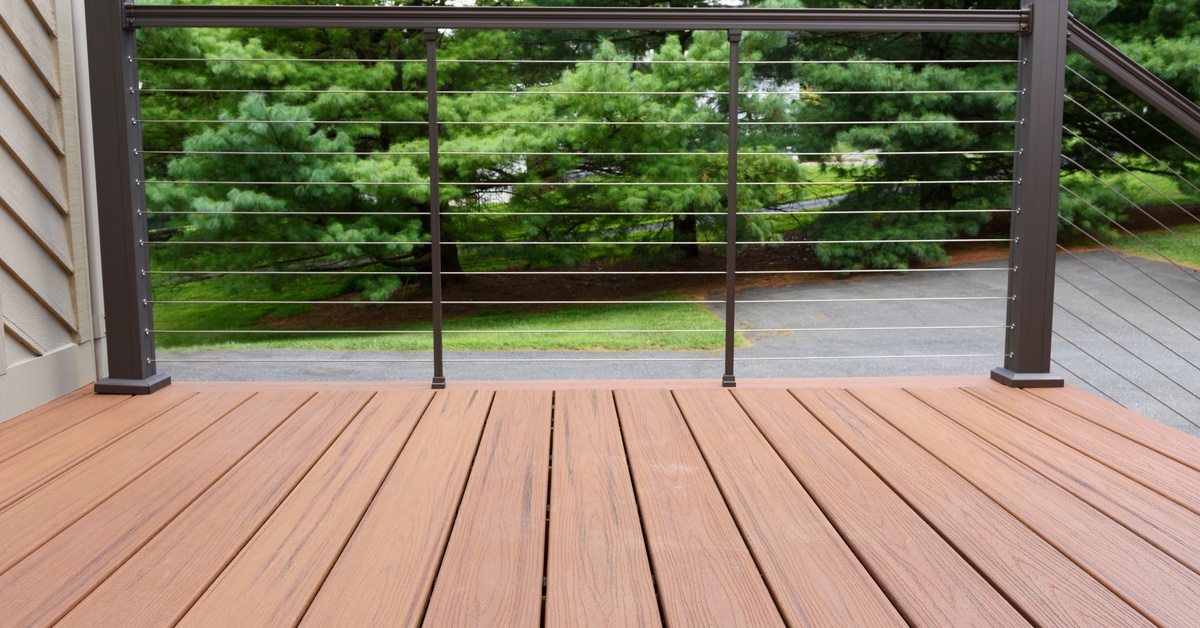 A wire deck railing with black posts. The deck itself is made of composite materials. There is a driveway behind the deck. A wire deck railing with black posts. The deck itself is made of composite materials. There is a driveway behind the deck.