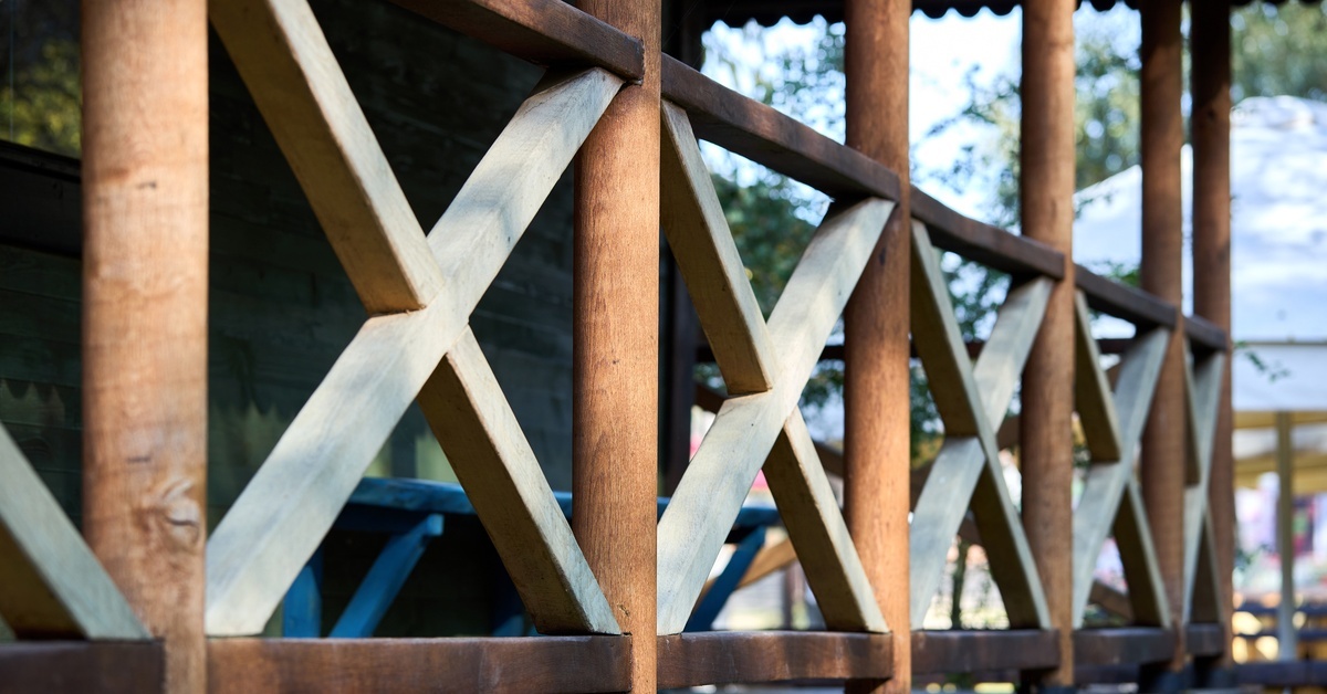 A deck with wooden railings that form an "X" between each post. There is a wooden bench against the wall of the house. A deck with wooden railings that form an "X" between each post. There is a wooden bench against the wall of the house.