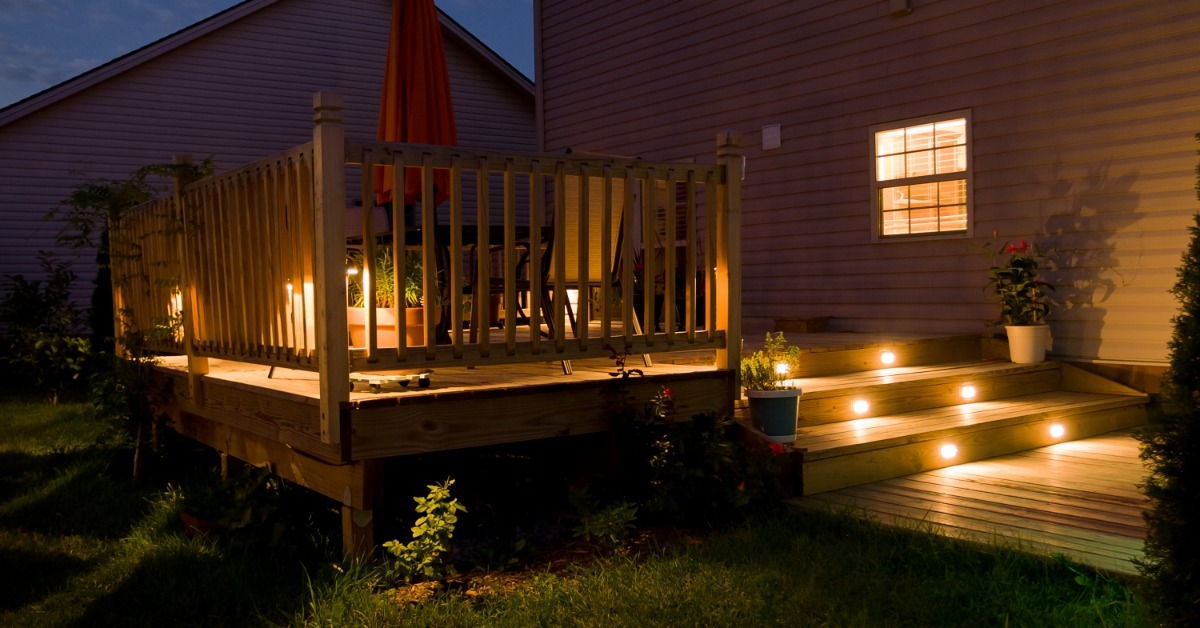 A wooden deck that has small lights all around it. The stairs have lights built into them for better visibility.